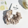 Détail d'un chouchou en satin doré champagne avec texture de soie lisse et volants - Style C / Rose Clair