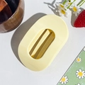 Detailed view of the large pale yellow oval hair claw clip set on a floral backdrop - Circular Clip / Milky Yellow