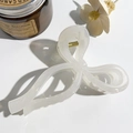 Dettaglio di un fermaglio a fiocco bianco crema con texture a nuvola e molla oro - Bianco Crema Trasparente