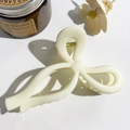 Detailed close-up of a creamy white bow-shaped hair claw clip with golden metal spring - Solid Cream White
