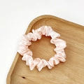 Macro detail of soft pink satin scrunchie with silky folds and elegant texture - Off White
