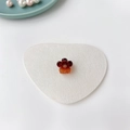 Detailansicht der Mini-Blumen-Haarklammer in Bernstein-Optik auf weißem Herz-Filz-Pad - Transparent Glänzend / Bernstein