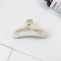 Detail view of cream-colored matte hair claw clip with a hollow streamlined design - Cream