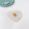 Vue détaillée d'une mini pince à cheveux fleur orange sur un plateau en céramique - Orange