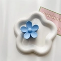 Detail showing the matte light blue flower hair claw clip on a white ceramic tray - Sky Blue