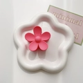 Close-up of a matte pink flower hair claw clip on a white decorative petal tray - Rose Red