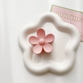 Détail d'une pince à cheveux fleur rose mate sur un plateau en céramique blanc - Rose chair