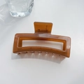 Macro shot of a large transparent amber square hair claw clip on a minimalist white background - Square Style Coffee
