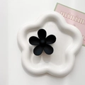 Close-up of matte black flower hair claw clip with minimalist floral design on white tray - Black
