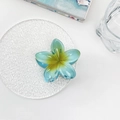 Detail der Haarklammer in blau-grüner Frangipani-Form auf einer weißen Servierplatte - Himmelblau Plumeria