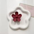Detail view of a matte dark red flower hair claw clip on a white ceramic tray - Burgundy