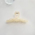 Close-up of cream-colored resin hair claw clip with twisted design and gold metal spring - Twisted Style Light Orange
