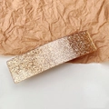 Close-up of elegant rectangular gold glitter hair clip with shimmering resin finish - Glitter Gold