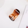 Detailed view of amber tortoiseshell claw clip with unique hollow infinity cross design - Glossy Amber