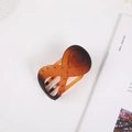 Close-up of matte amber infinity hair claw clip with geometric hollow design on a magazine - Matte Amber