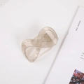 Detail of infinity hair claw clip in matte champagne acrylic on a neutral aesthetic background - Jelly Grey
