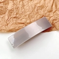 Close-up of a minimalist glossy taupe rectangular acetate hair clip on textured paper - Champagne