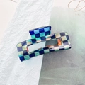 Detail showing checkered hair claw clip with blue and cream squares on a textured background - Large Square