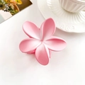 Detailed macro view of a matte pink plumeria hair claw clip on a white table - Gradient Pink