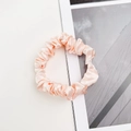 Gros plan d'un chouchou en satin rose montrant la texture brillante et plissée - Blanc Cassé