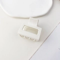 Macro shot of matte white square claw clip with geometric hollow design on ceramic tray - Matte Cream White