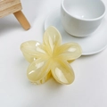 Detailed view of the matte yellow plumeria hair claw clip on a minimalist white desk - Jelly Milky Yellow