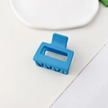 Macro di una molletta per capelli quadrata blu opaca su un vassoio in ceramica bianca - Blu Pavone Opaco