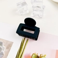 Detail of matte black rectangular hair claw clip with cutout design on a stylish card - Black