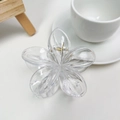 Top-down macro view of a matte flower hair claw clip with golden metal spring detail - Clear White