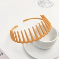 Close-up of orange matte plastic headband with teeth placed on a white coffee cup - Turmeric