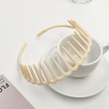 Detail of cream beige plastic headband with wide comb teeth resting on a coffee cup - Off White