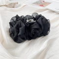 Nahaufnahme der großen schwarzen Organza-Rosen Haarklammer auf weichem Satin-Hintergrund - Schwarz