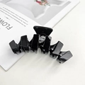 Detailed view of a large black acetate hair claw clip with a glossy finish on a magazine - Black