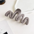 Vista dettagliata del fermaglio per capelli grigio opaco con design a onde su vassoio - Caffè Chiaro