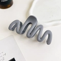 Detail view of a matte grey wavy hair claw clip styled on a minimalist tray background - 11cm Wave / Matte Blue Gray
