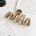 Close-up of matte wave hair claw clip in milk tea brown on a decorative white ceramic tray - 11cm Wave / Matte Ginger