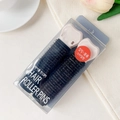 Detail of two black hair rollers with pink clips in a clear PVC display box on a desk - Plastic / Black