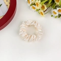 Close-up of a beige satin hair scrunchie with silky texture and elegant pleats on white - Off-white