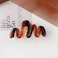 Detailed view of an amber wavy hair claw clip on a stylish decorative card - 11cm Wave / Jelly Amber