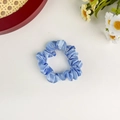 Detailed view of light blue satin scrunchie with silky texture on white background - Sky Blue
