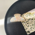 Detail view of iridescent beige acetate hair claw clip on black wood tray with daisy card - 8cm Square Head Claw Clip / Phantom Yellow