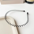 Detalle de diadema ondulada de metal negro con puntas protectoras sobre fondo blanco - Diadema Negra - Estilo Espiral