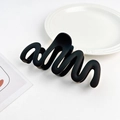 Detail of matte black wavy hair claw clip showing sleek S-curve design and frosted finish - Plastic/Resin / Black