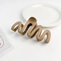 Detailed view of matte mocha wave hair claw clip on white ceramic plate with minimalist style - Plastic/Resin / Ginger Yellow