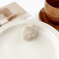 Gros plan d'une pince à cheveux en peluche douce sur un plateau en céramique minimaliste - Mini Rond Beige (3cm)