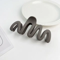 Close-up of matte dark grey wave hair claw clip on a white decorative porcelain plate - Plastic/Resin / Dark Coffee