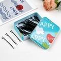 Dettaglio di forcine per capelli nere con una simpatica scatola di latta blu a cartoni - Piatto - Happy