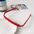 Vue détaillée d'un serre-tête carré rouge brillant sur un plateau de table blanc épuré - Bandeau Lunettes Carré - Rouge