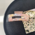 Detail view of large iridescent pink rectangular hair claw clip on black textured tray - 10.5cm Rectangle Claw Clip / Phantom Orange