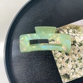 Macro detail of large translucent aurora green acrylic hair claw clip on black tray - 10.5cm Rectangle Claw Clip / Iridescent Green